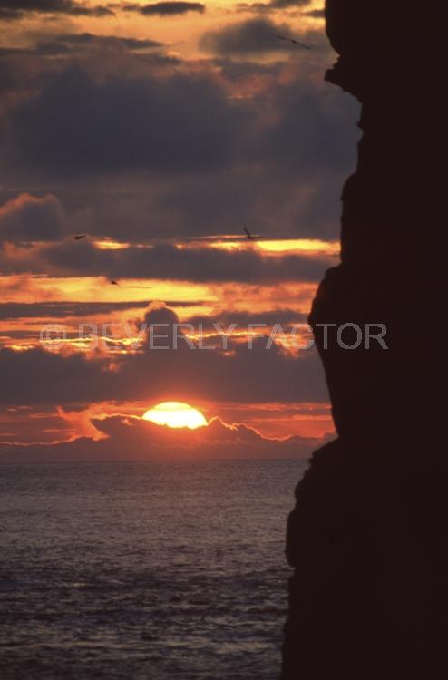 Islands;sunsets;sky;clouds;colorful;sun;yellow;water;red;sillouettes;Galapogos Island